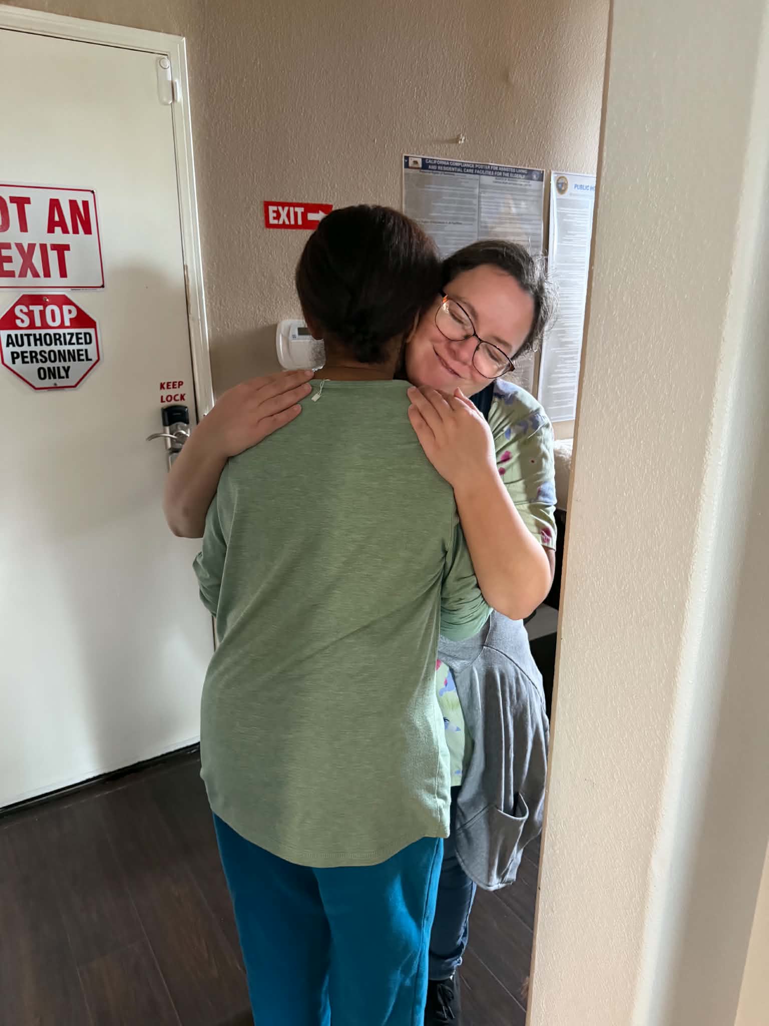 Ms. Robin holding JES in a gentle, reassuring embrace