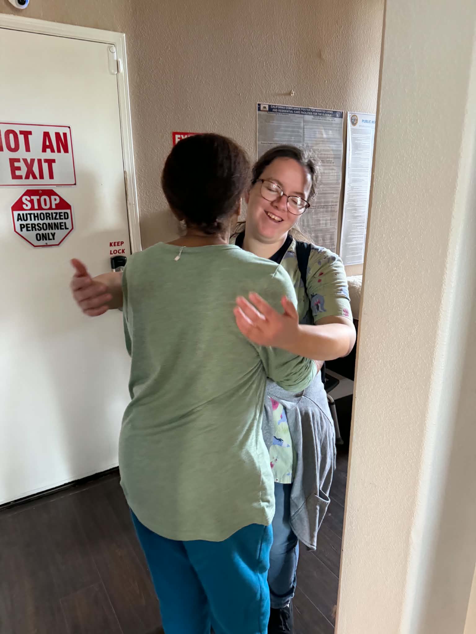 Ms. Robin smiling warmly as she welcomes JES into another embrace